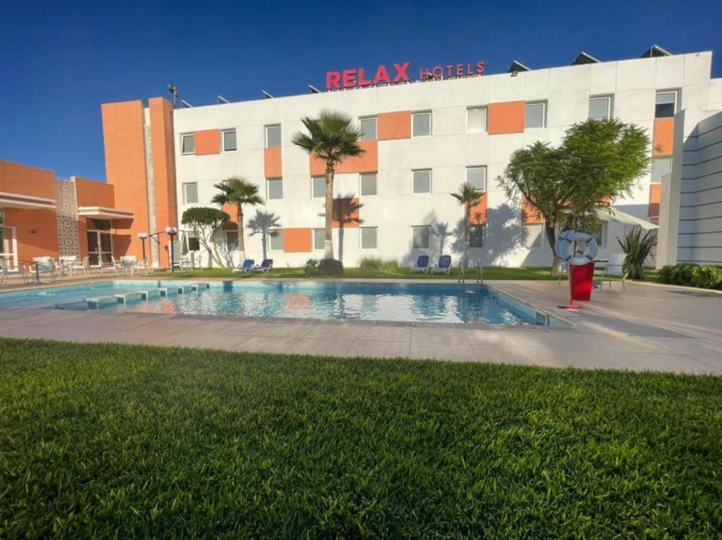 a hotel with a swimming pool in front of a building at Relax Hotel Kenitra in Kenitra