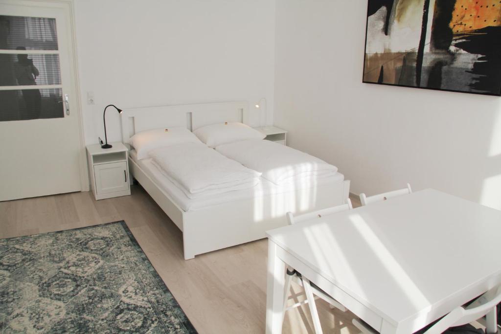 a white bedroom with a white bed and a table at Vienna4you App 33 you are welcome in Vienna