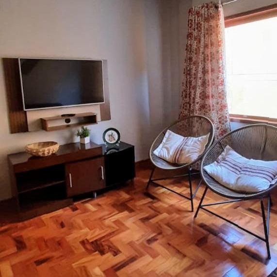 a living room with two chairs and a flat screen tv at Apto Tranquilo e Aconchegante no Centro de Águas de Lindoia in Águas de Lindoia