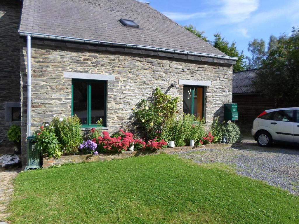 une maison en pierre avec des fleurs dans la cour dans l'établissement Le fenil, à Cornimont