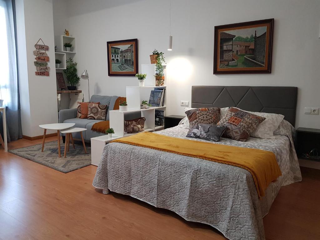 een slaapkamer met een bed, een bank en een stoel bij ESTUDIO IDEAL PARA VACACIONES Y TRABAJO in Vigo