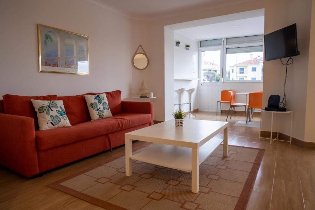 a living room with a red couch and a table at Spacious and Sunny Apartment - 10 min from the sea in Estoril
