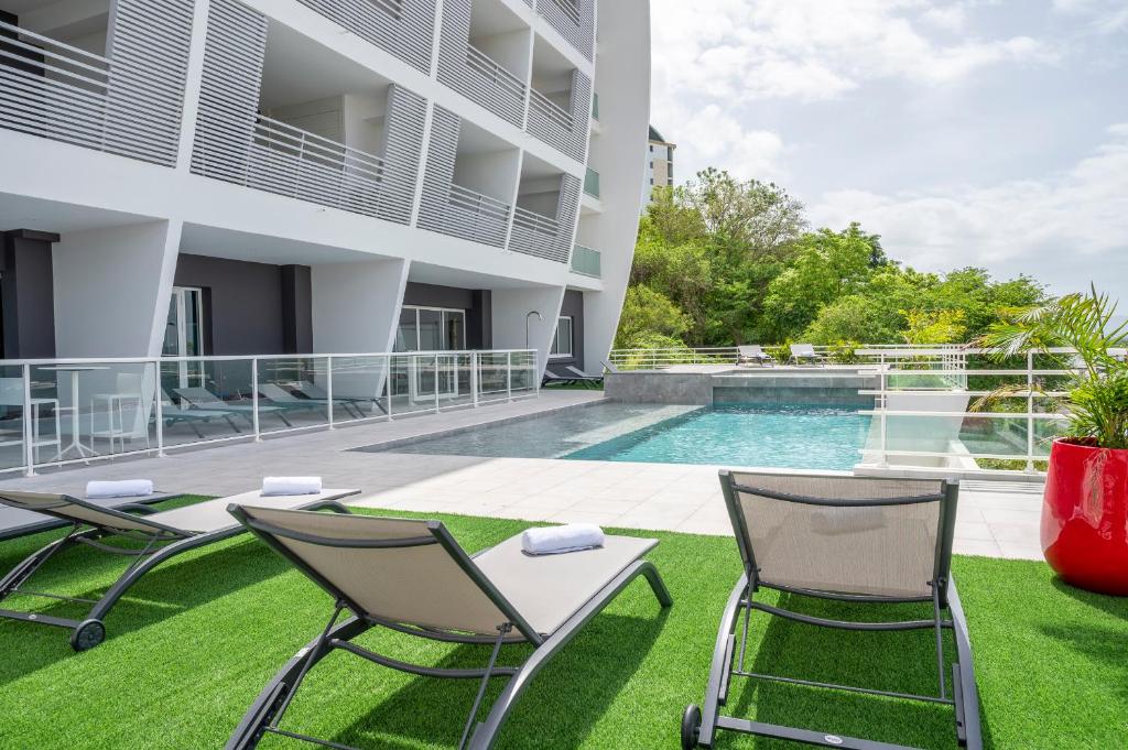 an apartment patio with chairs and a swimming pool at Résidence Hôtelière Poséidon Caraïbes in Fort-de-France