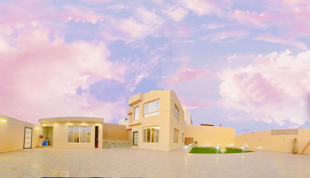 a white house with a cloudy sky in the background at شاليه العبير in Buraydah