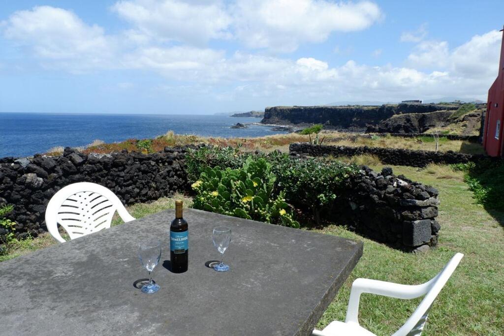 a table with a bottle of wine and two glasses at Coastal Trail Cottage in São Vicente Ferreira