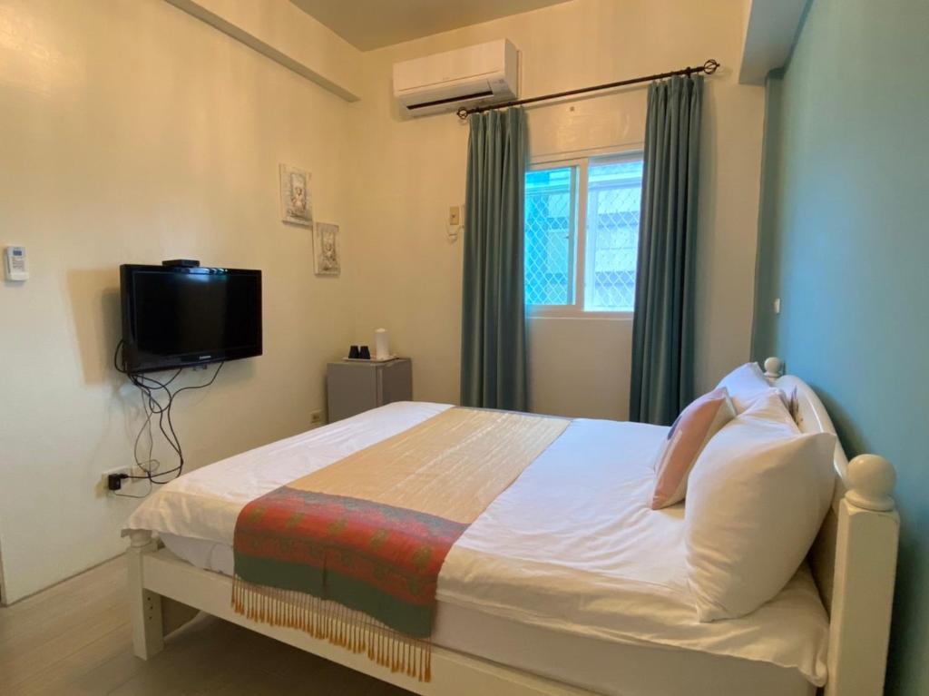 a small bedroom with a bed and a tv at Beauty Home Homestay in Hualien City
