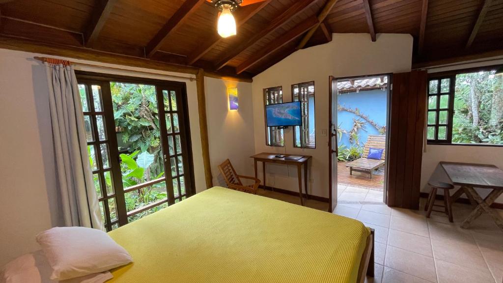 a bedroom with a yellow bed in a room with windows at Casa Jardim Bangalos in Paraty