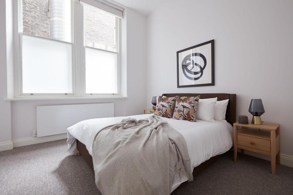 a white bedroom with a bed and two windows at 1VH Virginia House, 31 Bloomsbury Way by City Living London in London