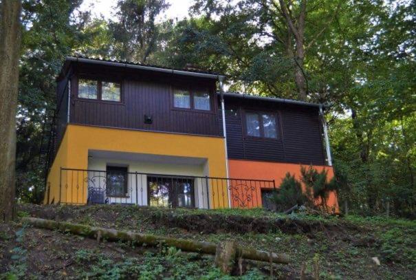 a yellow and orange house in the woods at Irma- forrás Vendégházak in Kismaros