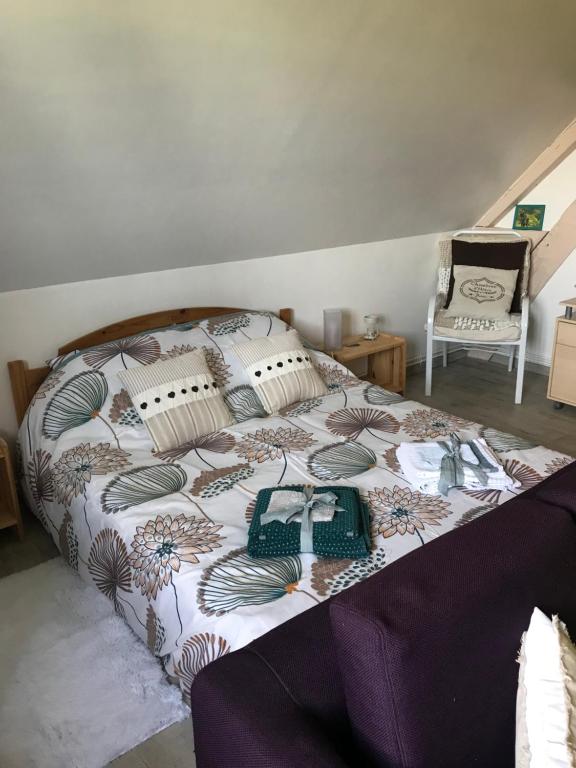 a bedroom with a bed with a blanket and a chair at La Marokanette in Saint-Maclou-de-Folleville