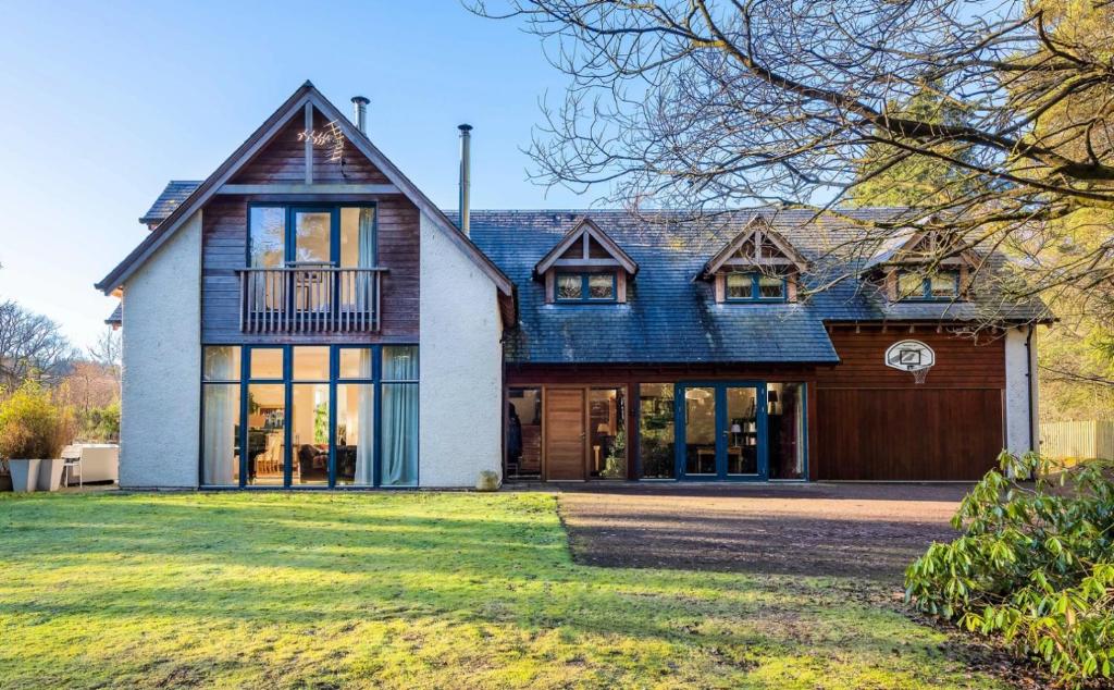 een huis met een gambrel dak en een garage bij Glenardle Lodge in Bridge of Cally