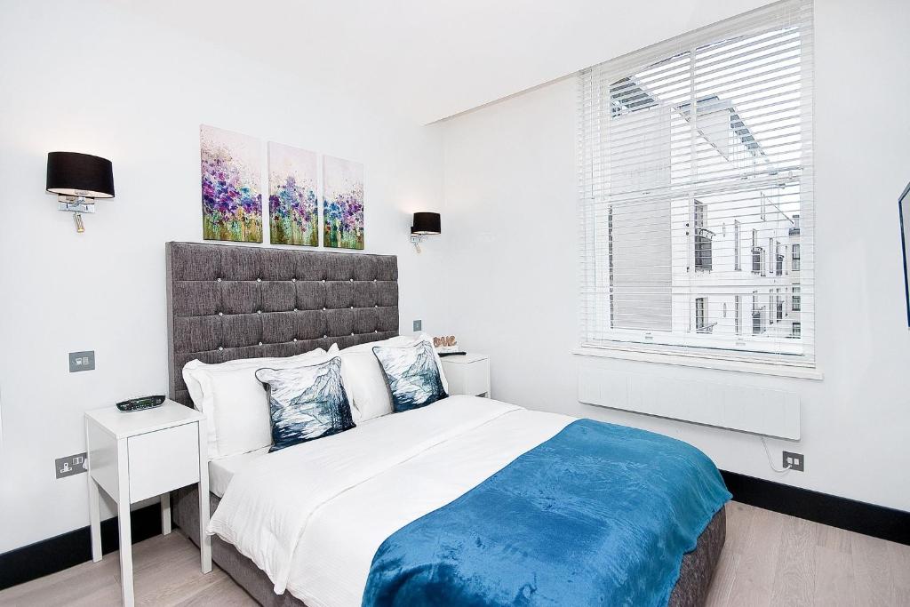 a white bedroom with a large bed and a window at Heinze Flat 402 - One bedroom fourth floor flat By City Living London in London