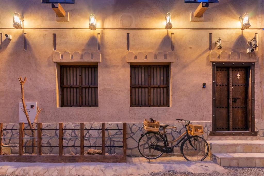 a bike parked in front of a building with two windows at Bait Alharah in Al Jināh
