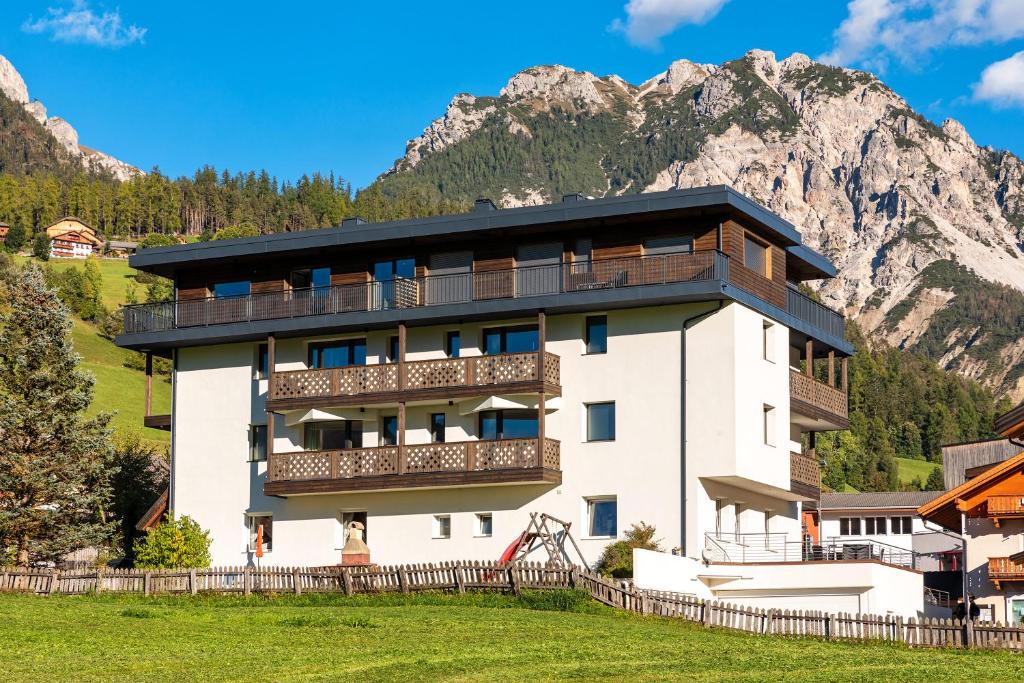 a building with a balcony and mountains in the background at Residence Catarina Lanz in San Vigilio Di Marebbe