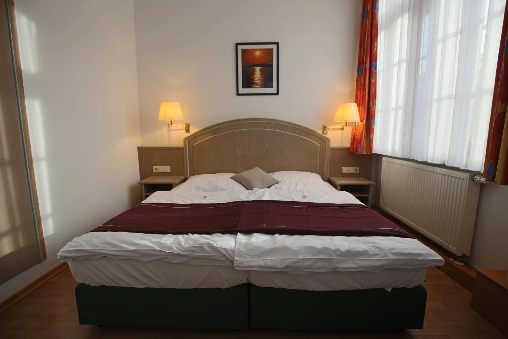 Bett in einem kleinen Zimmer mit zwei Fenstern in der Unterkunft Hotel Restaurant Hambacher WInzer in Neustadt an der Weinstraße