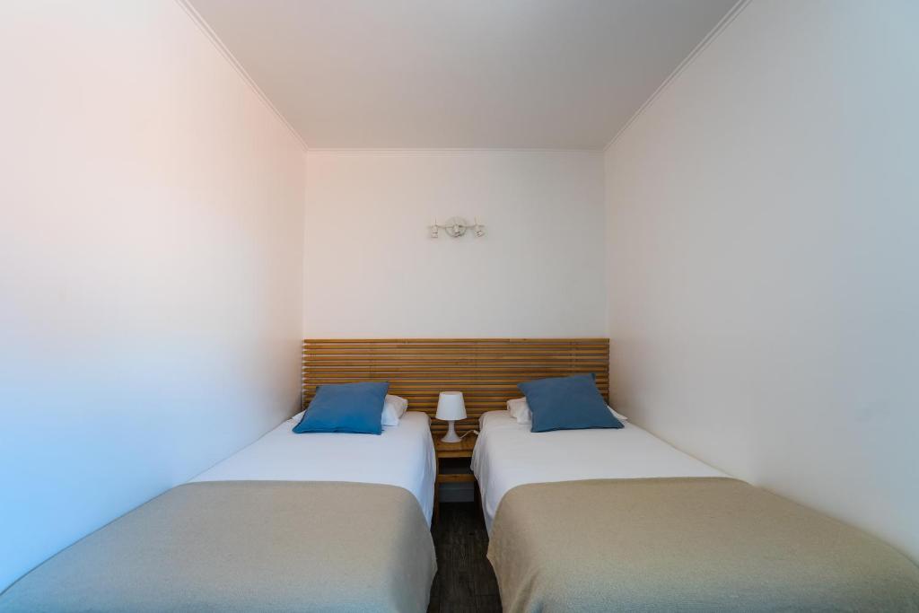 two beds in a room with white walls and blue pillows at Quinta da Bicuda in Cascais