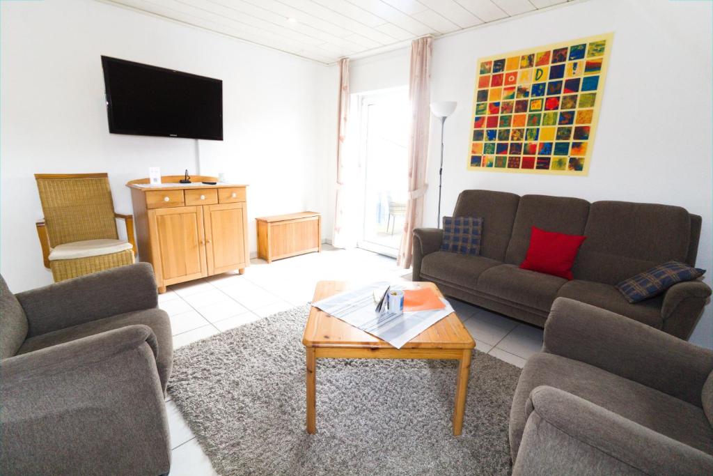 een woonkamer met banken en een flatscreen-tv bij FeWo Heitkamp in Dornumersiel