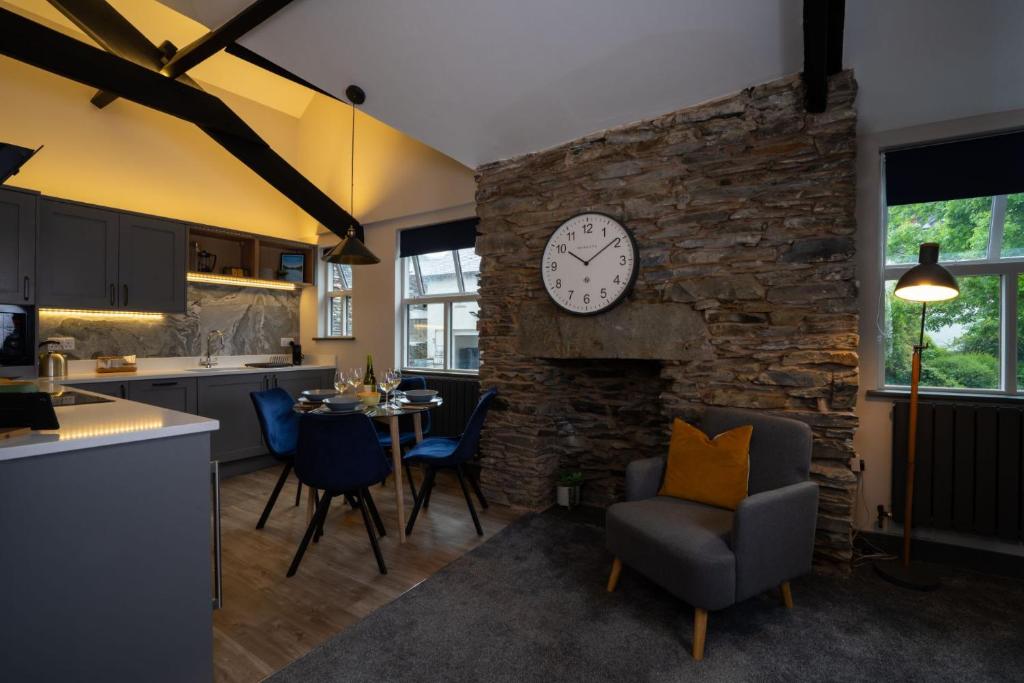 a kitchen and dining room with a clock on a stone wall at Spacious - Contemporary 2BR Apartment - Central Ambleside - Parking in Ambleside