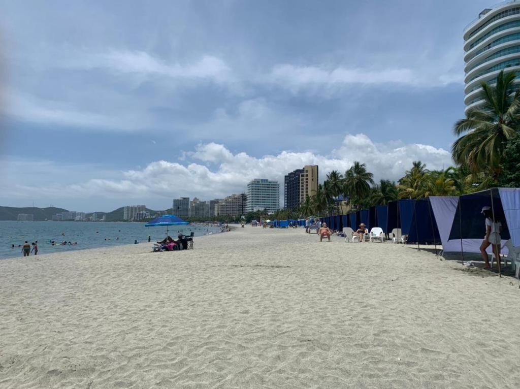 a beach with people and the ocean and buildings at Hotel West Plaza in Santa Marta