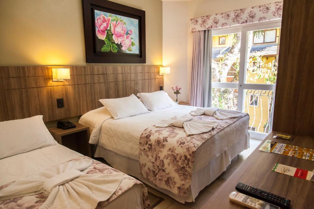 a hotel room with two beds and a window at Pousada Águia Branca in Gramado
