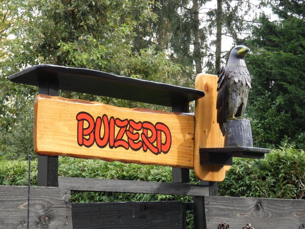 une statue d'un aigle assis sur un panneau dans l'établissement Chalet Buizerd in Koudhoorn #omgeven door bos# tussen Garderen en Putten, à Putten