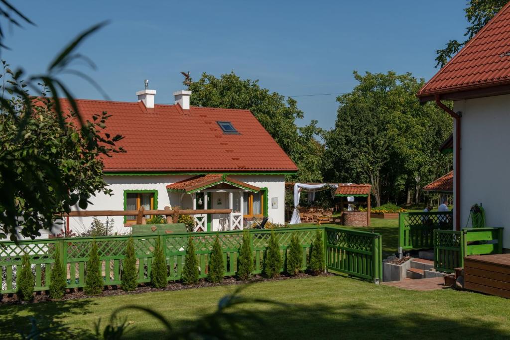 uma casa com um telhado vermelho e uma cerca verde em Zielony Domek w Nartach - Mazury em Narty