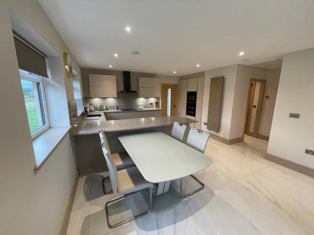a kitchen with a white table and chairs in it at Lux Cottage in Blackburn