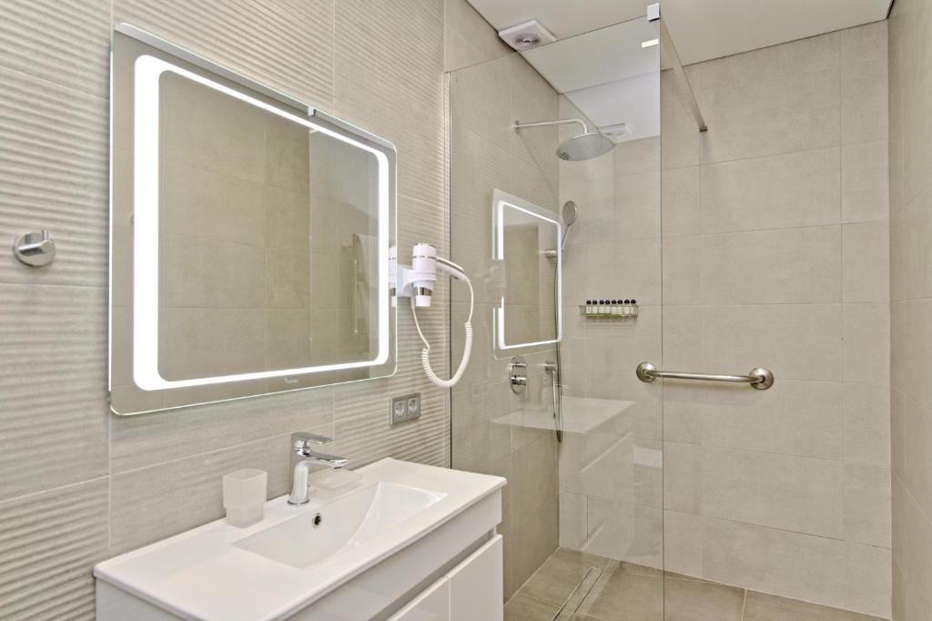 
a bathroom with a sink, mirror, and shower stall at Deribas Hotel in Odesa
