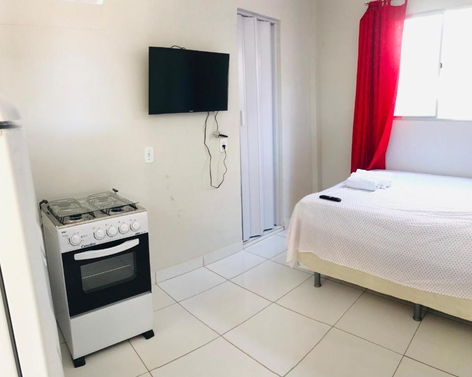 a kitchen with a stove and a bed in a room at Aconchego em Parnaíba JW. 2 in Parnaíba