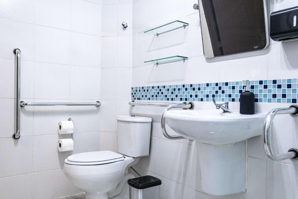 a white bathroom with a toilet and a sink at HOSTEL CUARTO in Sao Paulo