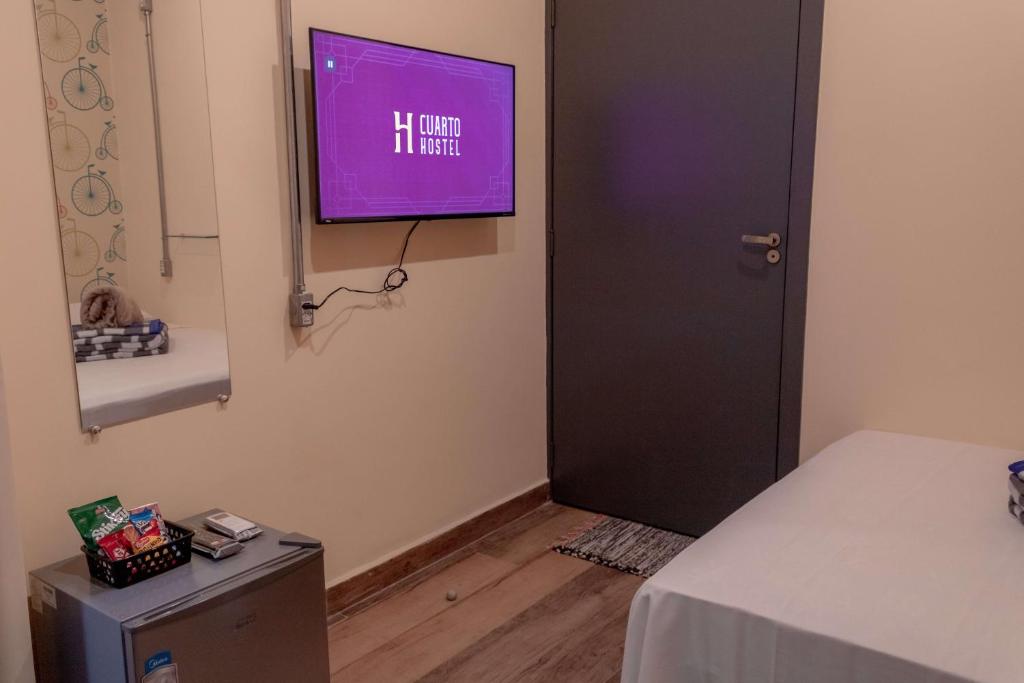 a room with a tv on the wall next to a door at HOSTEL CUARTO in Sao Paulo