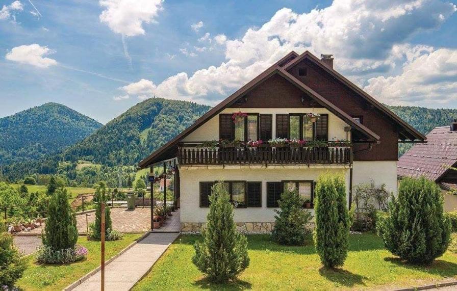 a house with a balcony and mountains in the background at Apartman Svetličić in Ravna Gora