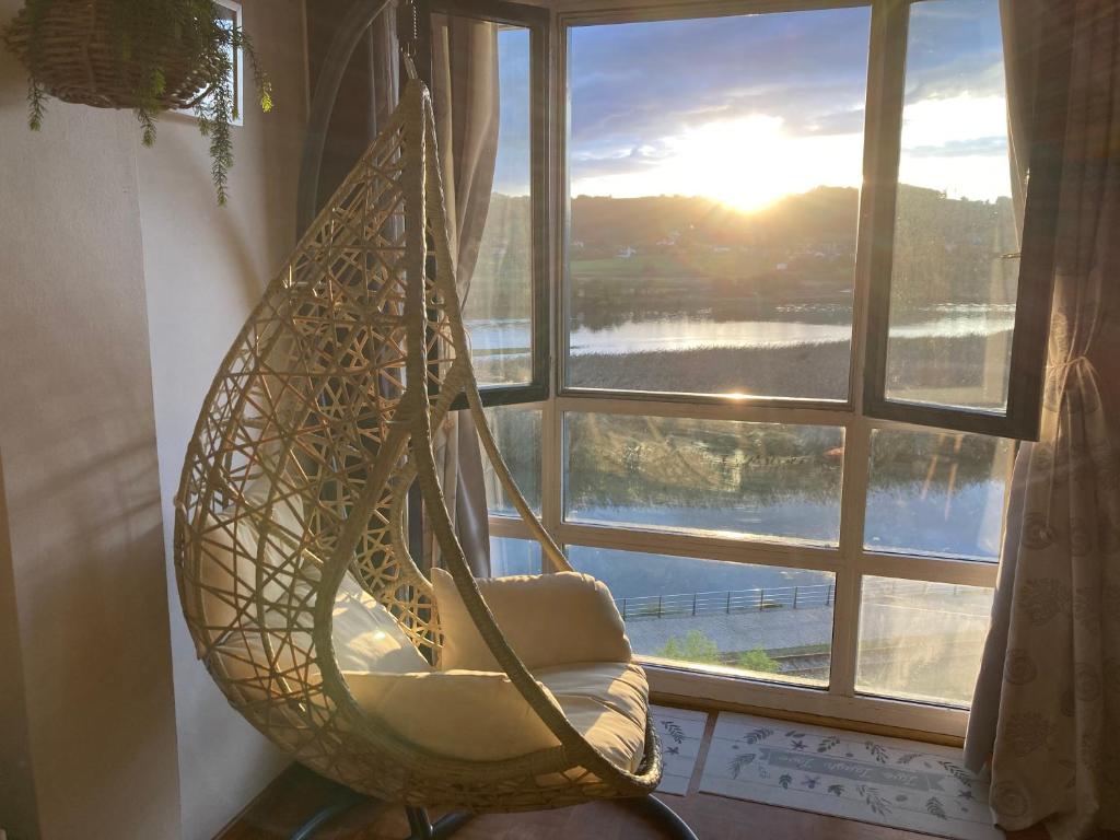 a hanging hammock in a room with a window at Apartamento con vistas espectaculares al rio Sella in Ribadesella