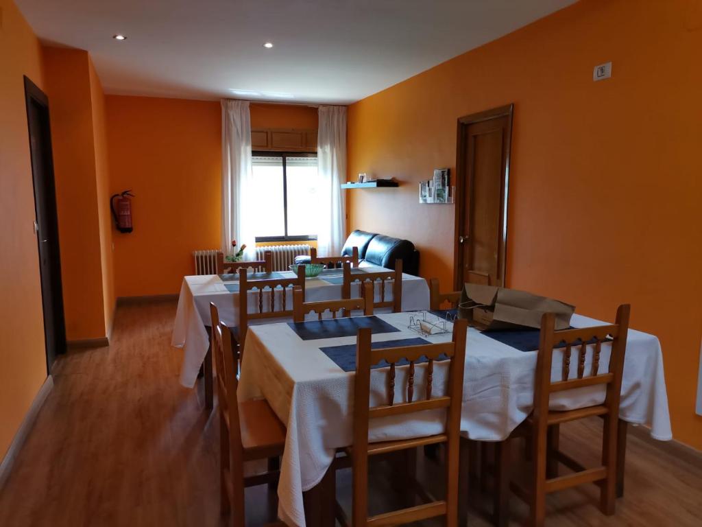 comedor con 3 mesas y sillas y paredes de color naranja en apartamento Laza, en Laza