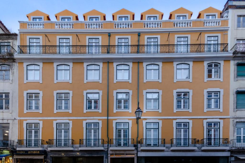 pomarańczowy budynek z balkonem na górze w obiekcie Rossio Plaza Hotel w Lizbonie