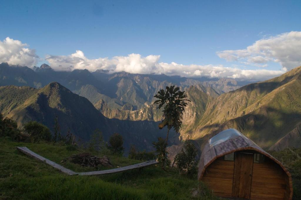 a wooden hut on a hill with mountains in the background at Machupicchu EcoLodge in Cusco