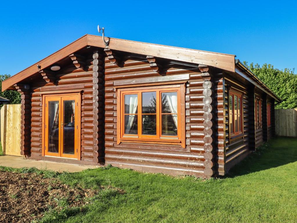 a log cabin with windows on a lawn at Elm Lodge in Oakham