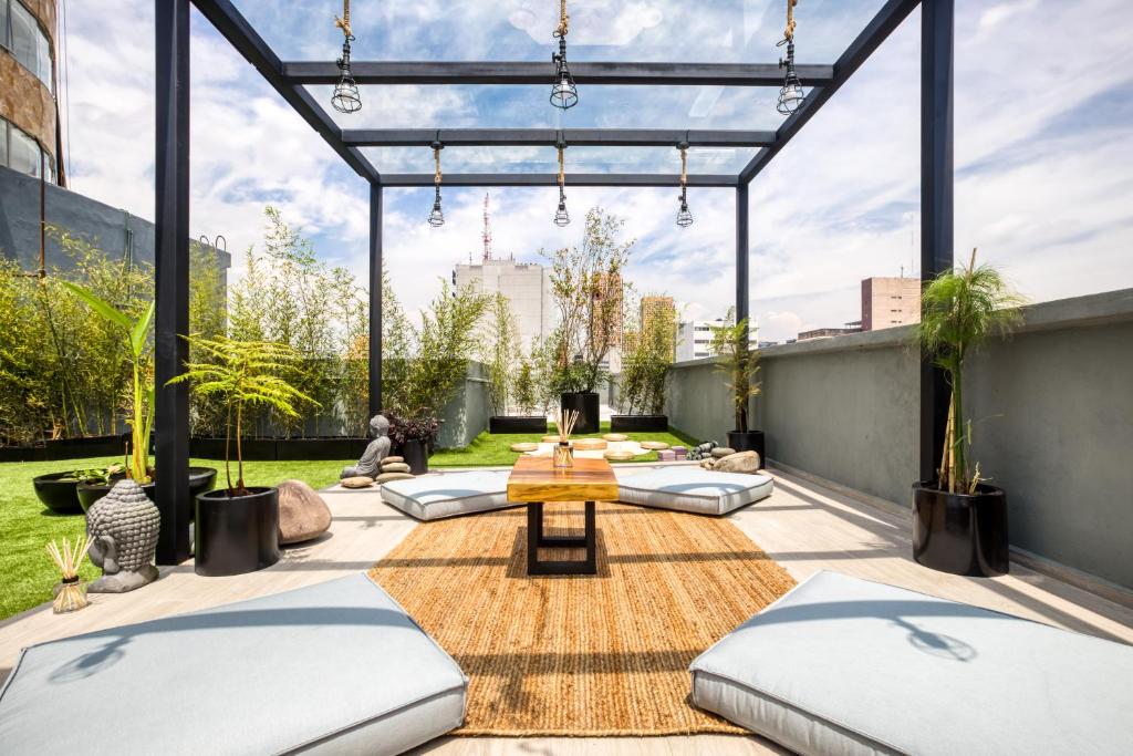 a patio with pillows and a table on a roof at ULIV Luxe Apartments Polanco in Mexico City