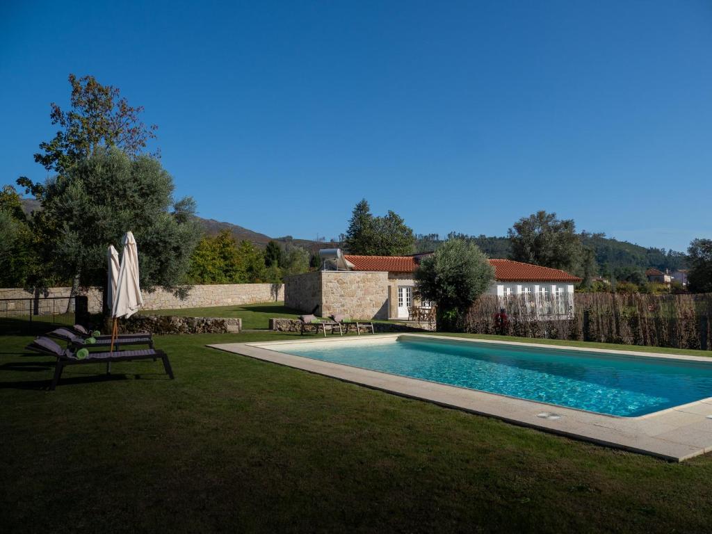 a swimming pool in a yard with an umbrella at Casa da Portelinha in Arcos de Valdevez