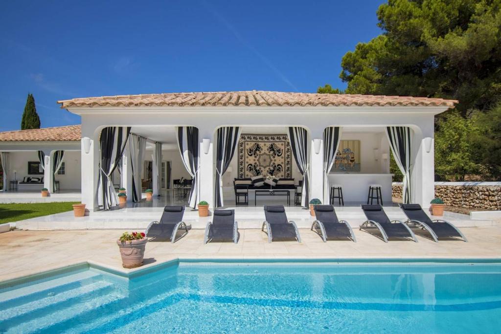 a swimming pool with chairs and a gazebo at Menorca Villa Marbella in Son Parc
