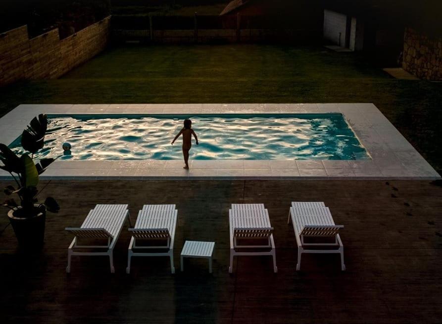 una mujer parada en una piscina con cuatro sillas en ACASADETEO, en Padrón