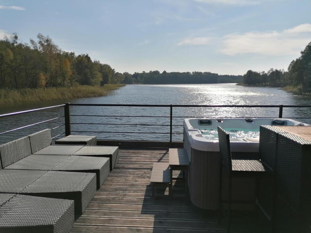 a deck with chairs and a bath tub on a body of water at Dom na wodzie in Piecki