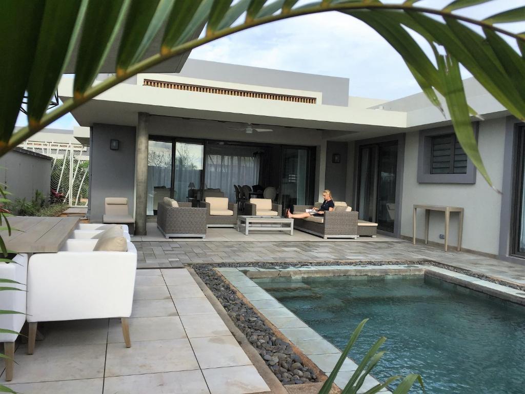 una villa con piscina e una donna seduta su un divano di Luxury Villa at Royal Park Sandpiper a La Bergerie