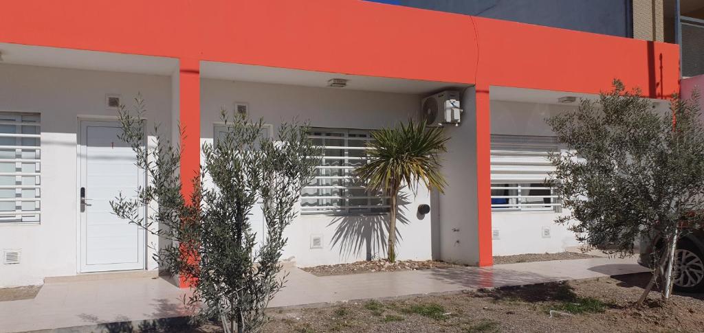 un edificio de color naranja y blanco con puertas y árboles en Pewmafe en Las Grutas