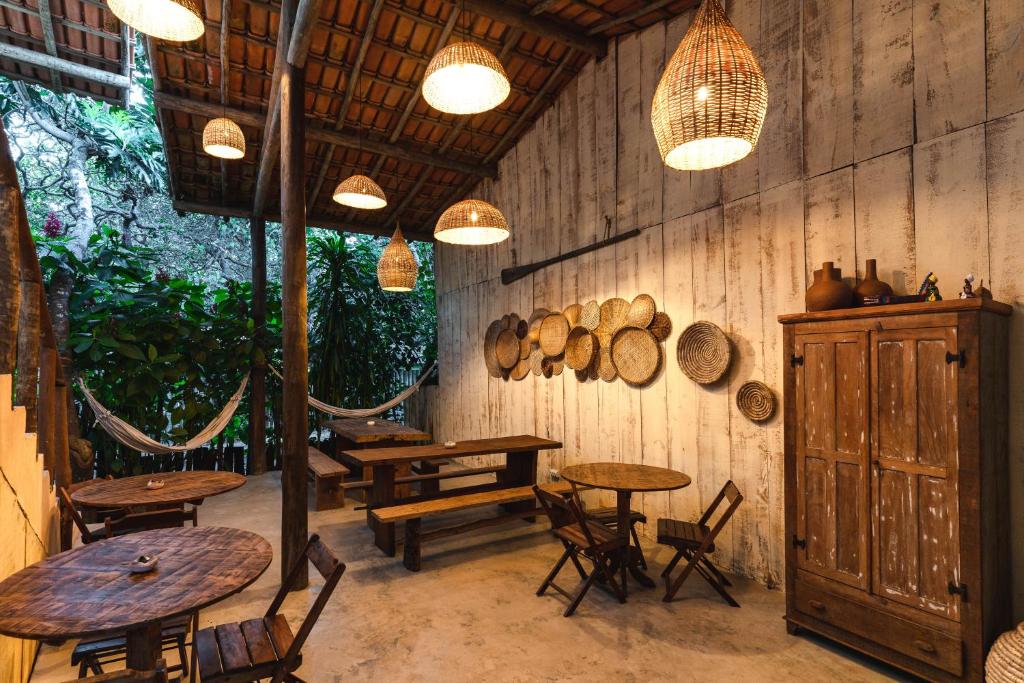 um restaurante com mesas e cadeiras e barris e luzes em Casa da Esquina Caraíva em Caraíva