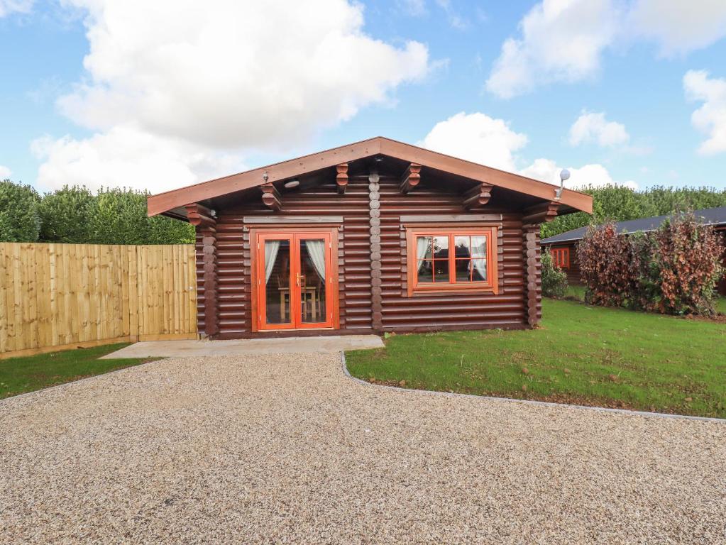 uma cabana de madeira com uma cerca e um quintal em Maple Lodge em Oakham