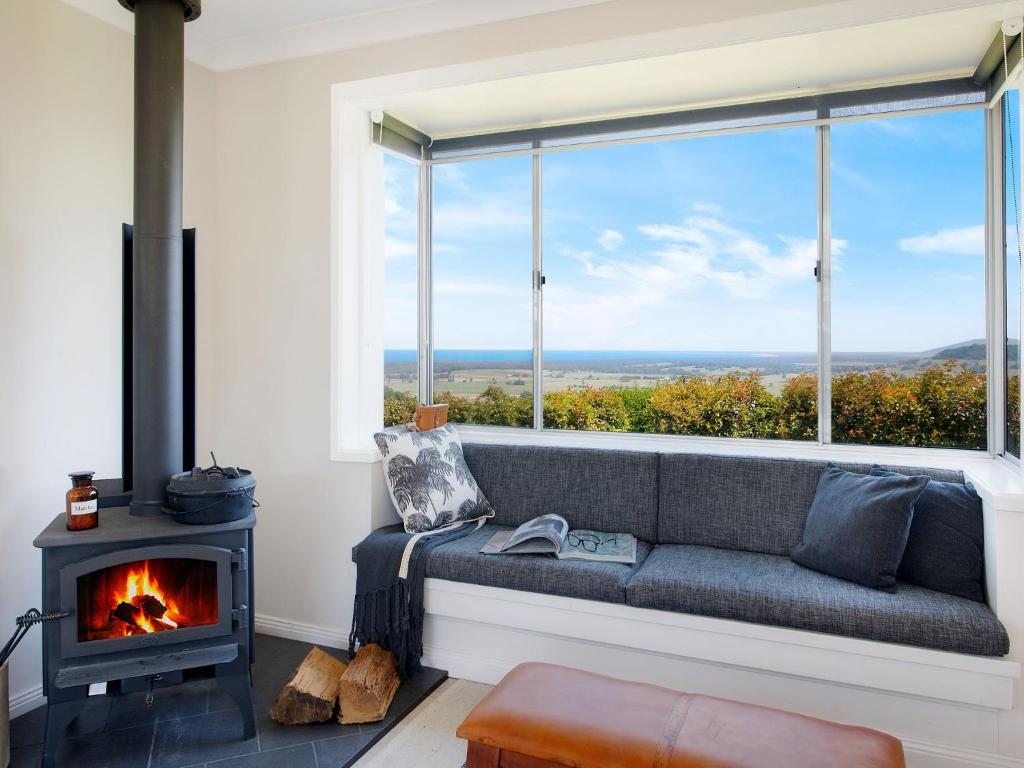 a couch in a room with a fireplace and a window at Ocean Willow Gerringong in Gerringong