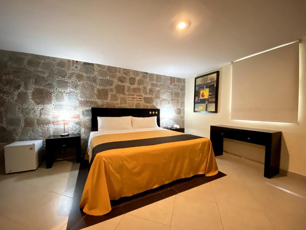 a bedroom with a bed and a brick wall at Hotel Escala Puebla Centro in Puebla