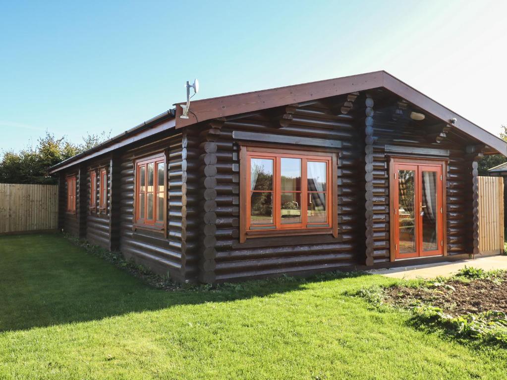 Cabaña de madera con ventanas y patio en Rowan Lodge en Oakham