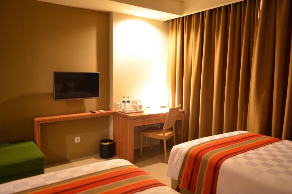 a hotel room with two beds and a desk with a television at Kyriad Hotel Airport Jakarta in Tangerang